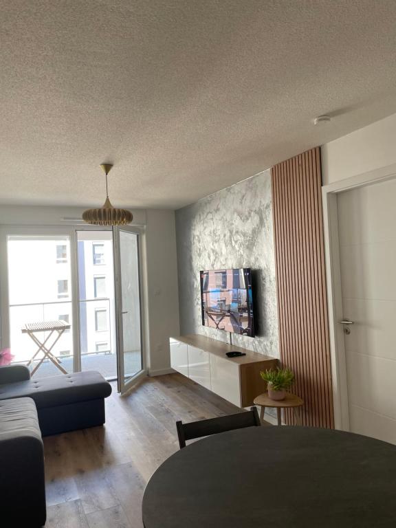 ein Wohnzimmer mit einem Sofa und einem TV an der Wand in der Unterkunft Marcopolo Luxury Appartement in Bischheim