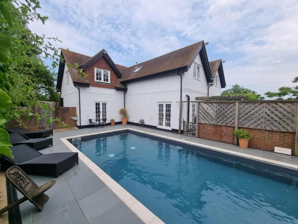 una piscina frente a una casa en New Forest Cottage alongside Limewood Lyndhurst, en Lyndhurst
