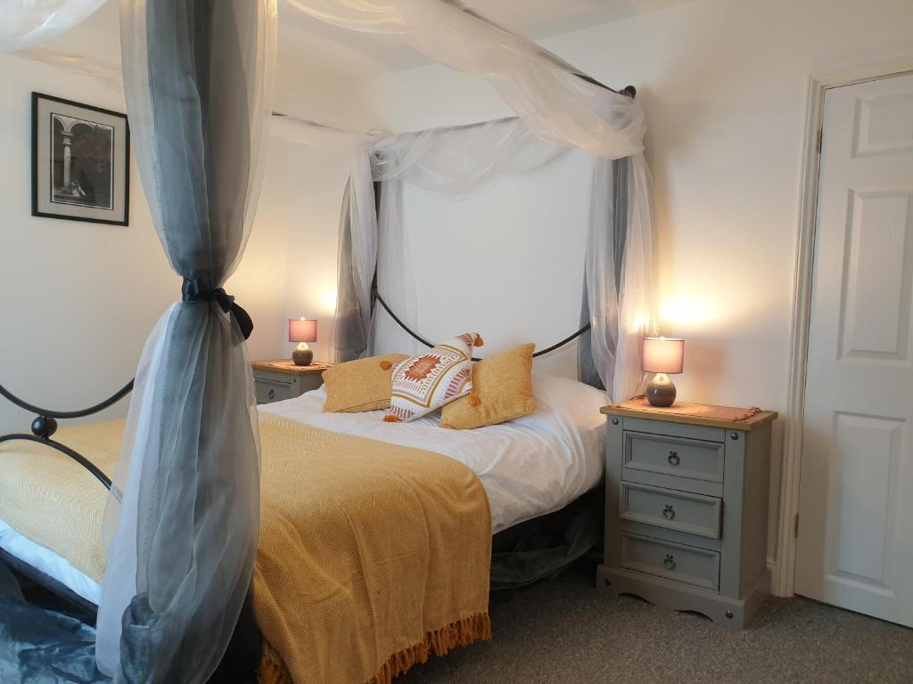 una camera con un letto a baldacchino sopra di Quaint cottage near to town, beach and station a Exmouth