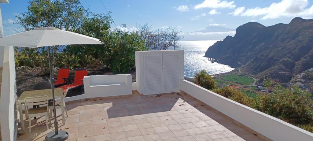 een patio met een parasol en uitzicht op de oceaan bij Casa Lita in Hermigua