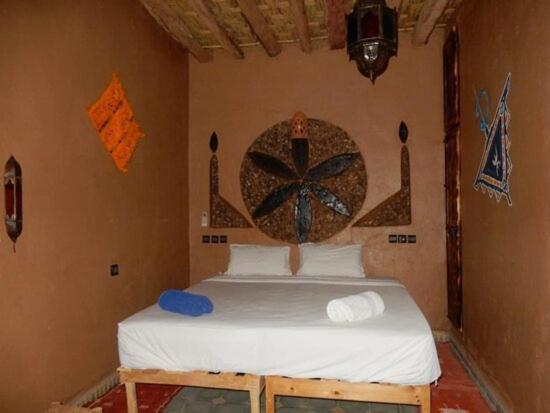 - une chambre avec un lit orné d'une peinture murale dans l'établissement M'hamid Adventures, à Mhamid