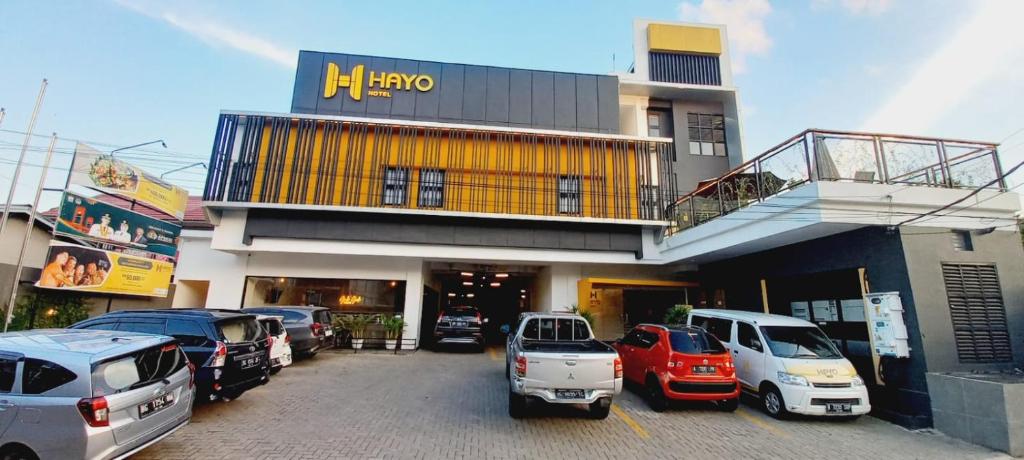 un estacionamiento con autos estacionados frente a un edificio en Hayo Hotel Palembang, en Sukarami