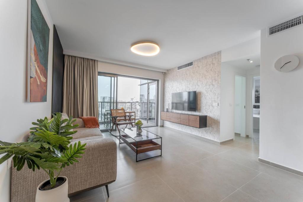 a living room with a couch and a tv at Holysuite Savyon View Tower in Jerusalem