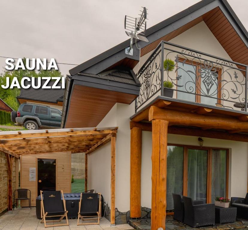 ein Haus mit einem Balkon und Stühlen auf einer Terrasse in der Unterkunft Gorczański Resort Domek w Górach Sauna Jacuzzi in Nowy Targ