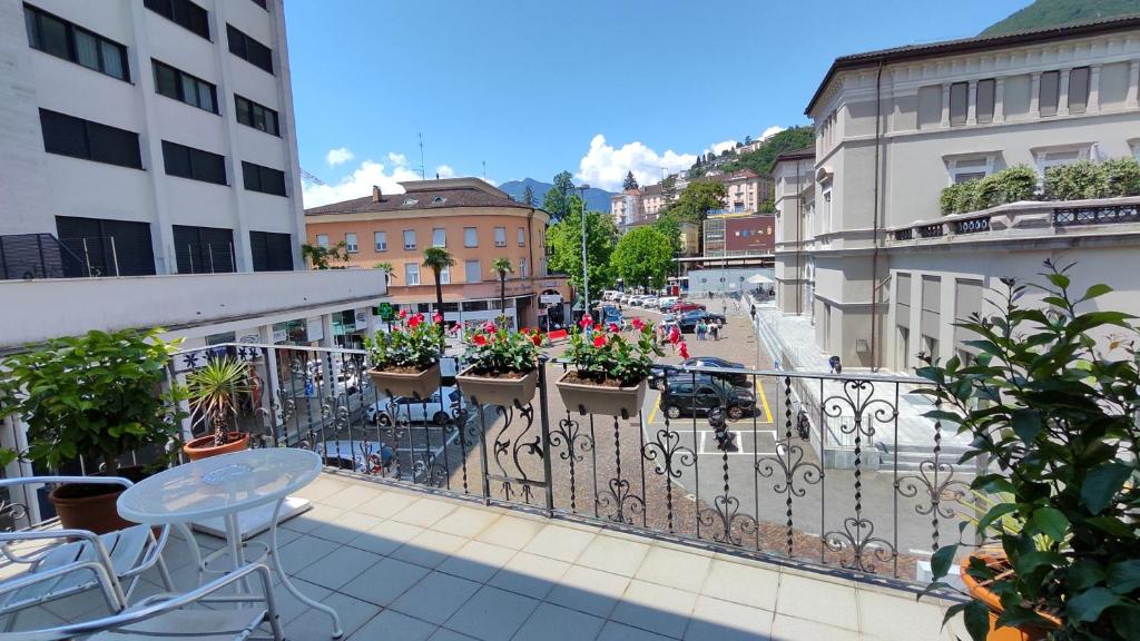 een balkon met een tafel, stoelen en bloemen bij Hotel Scaletta in Locarno