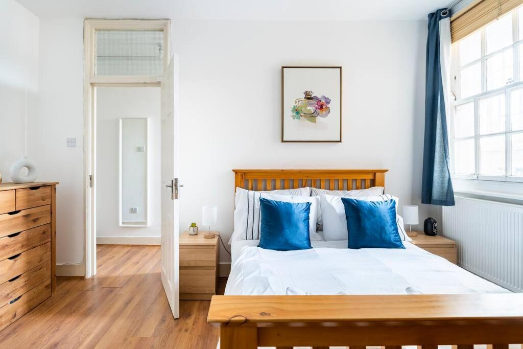 a bedroom with a large bed with blue pillows at Cozy Apt in Central London in London