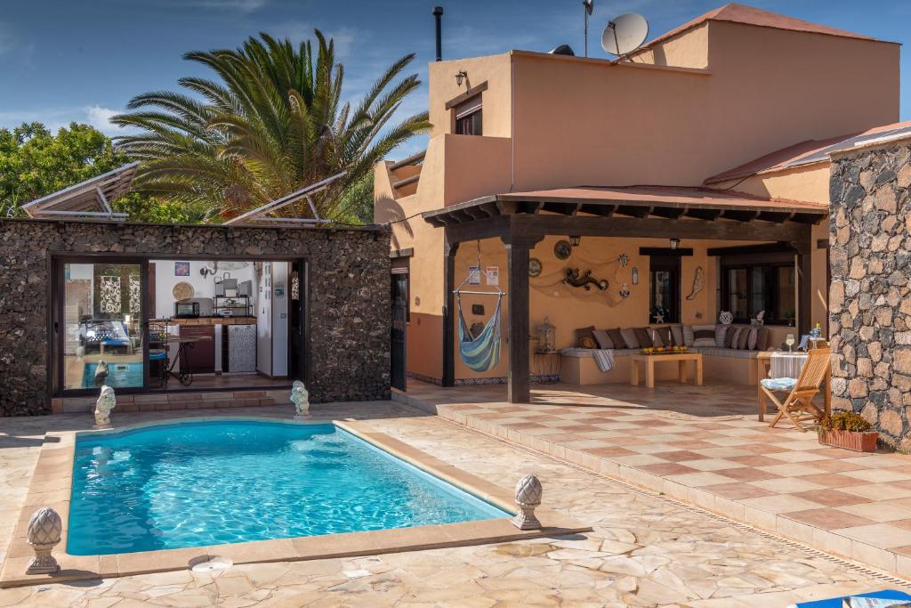 a villa with a swimming pool in front of a house at Villa Maravilla piscina climatizada in Villaverde