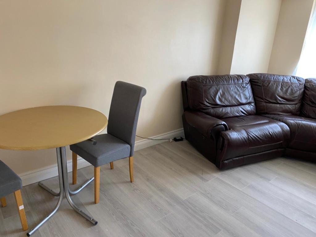 a living room with a table and a leather couch at A home away from home in Dagenham