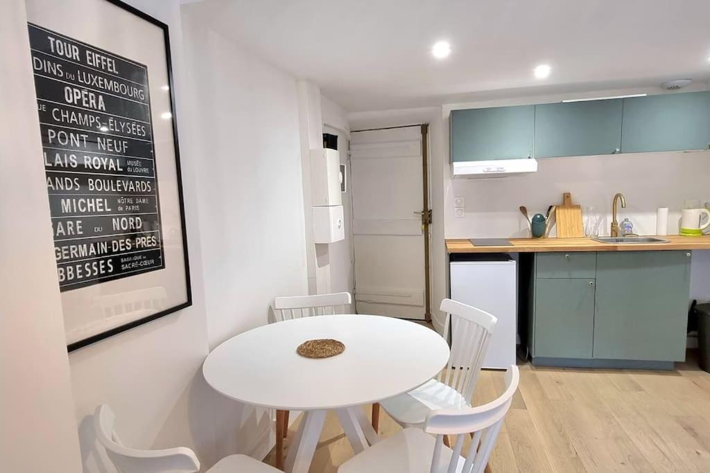 a small kitchen with a white table and chairs at Dans les nuages - T2 Spacieux Standing - Metro - Wifi in Toulouse