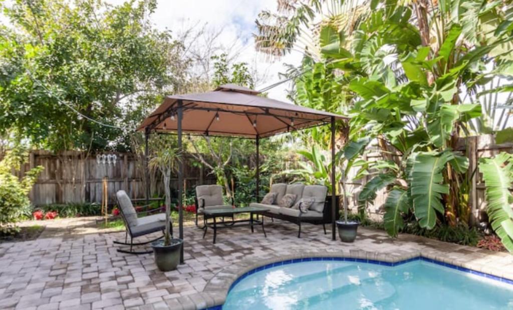 eine Terrasse mit einem Tisch, Stühlen und einem Sonnenschirm in der Unterkunft Our boutique Fort Lauderdale guest house in Fort Lauderdale