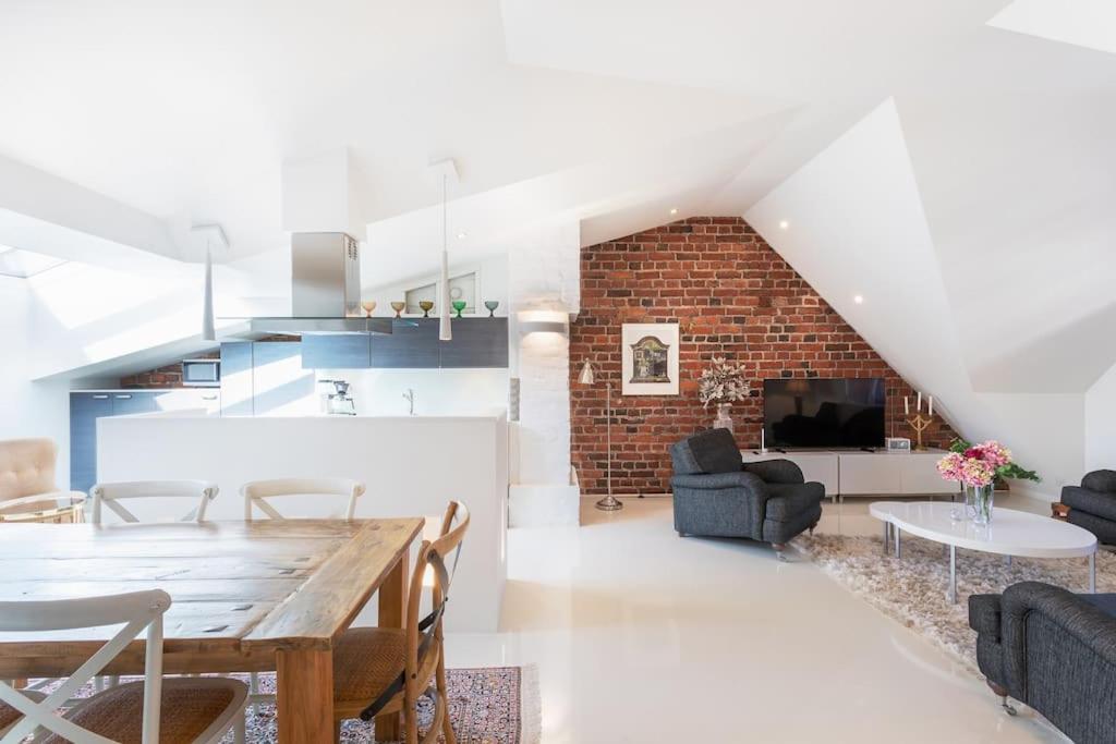 a dining room and living room with a brick wall at Stunning Huvilakatu Penthouse in Helsinki