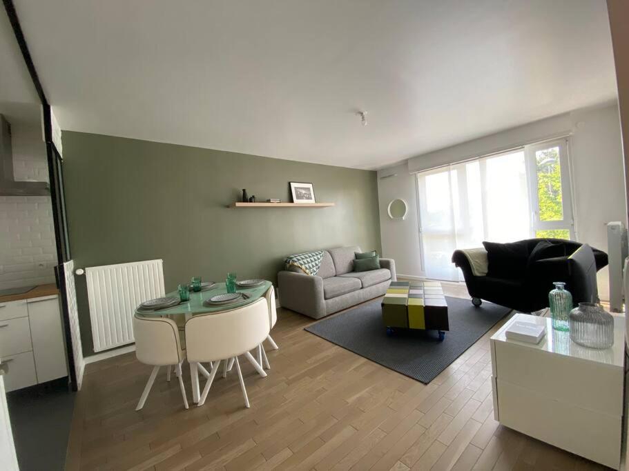 uma sala de estar com uma mesa e um sofá em Appartement proche Paris & Orly em Chevilly-Larue