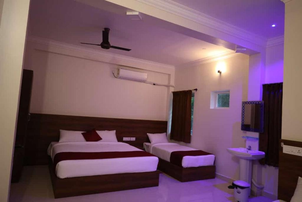een hotelkamer met 2 bedden en een televisie bij CHANDRODAYAM RESIDENCY in Kāraikāl