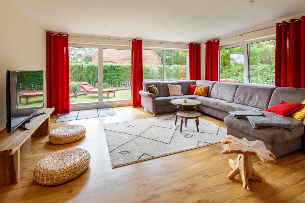 a living room with a gray couch and red curtains at Villa Agni in Dänschendorf