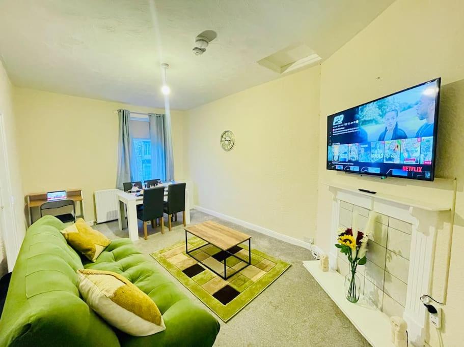 a living room with a green couch and a flat screen tv at Darlington City Flat in Darlington