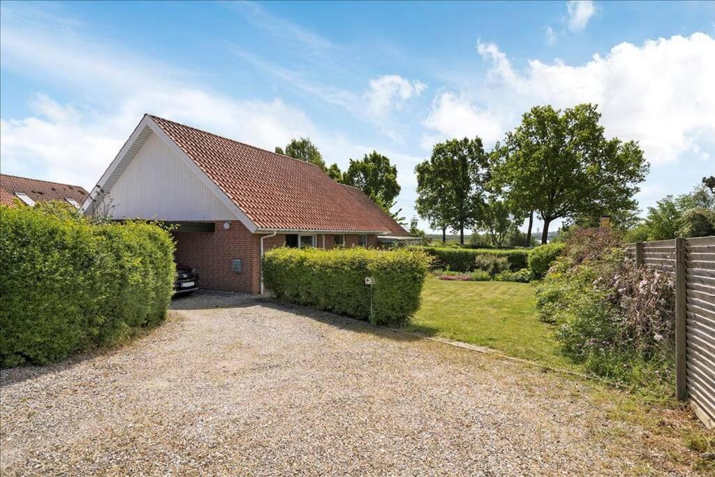 a house with a fence and a gravel driveway at House near public transport in Lystrup