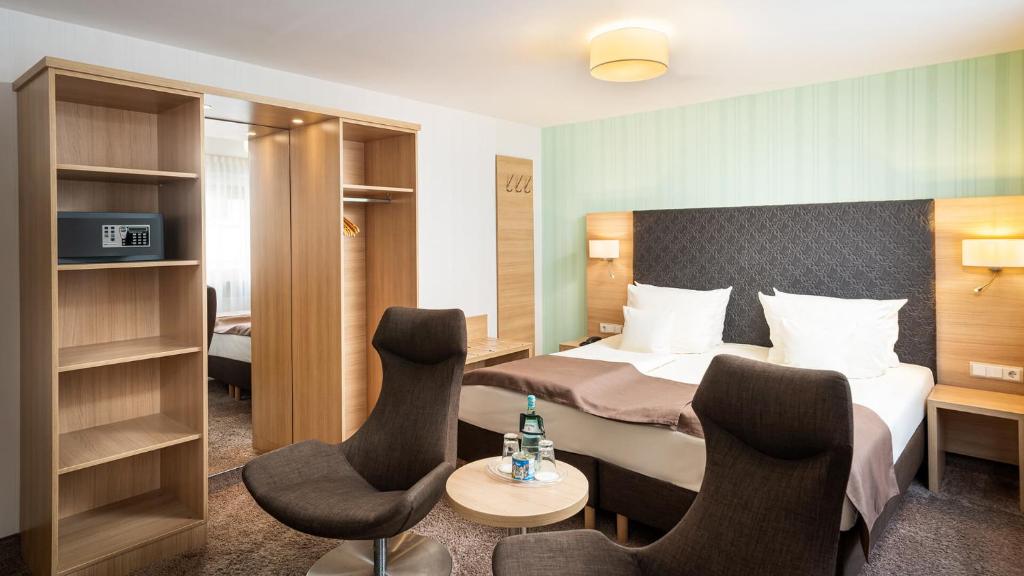 リューデスハイム・アム・ラインにあるリングホテル セントラル スーペリアのベッド1台と椅子2脚が備わるホテルルームです。