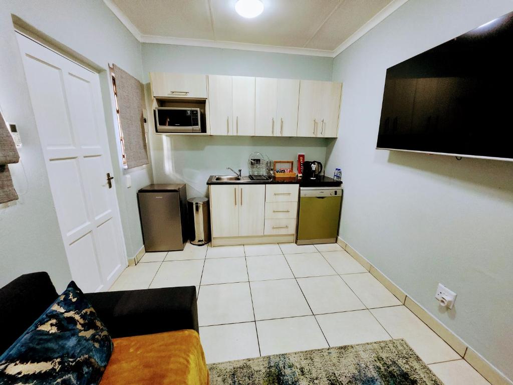 a small kitchen with white cabinets and a black couch at 136 on 4th in Johannesburg
