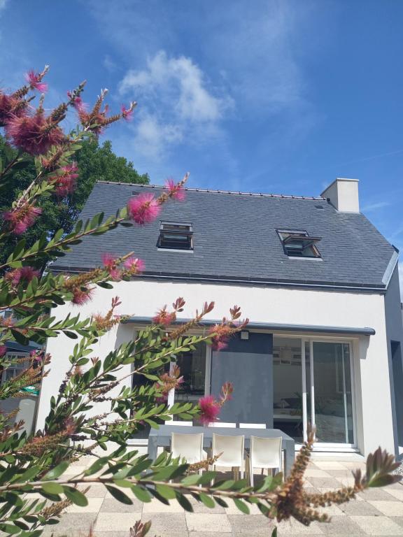 a white house with pink flowers in front of it at Maison tout confort au calme à 300m de la mer et du GR34 avec jardin in Loctudy