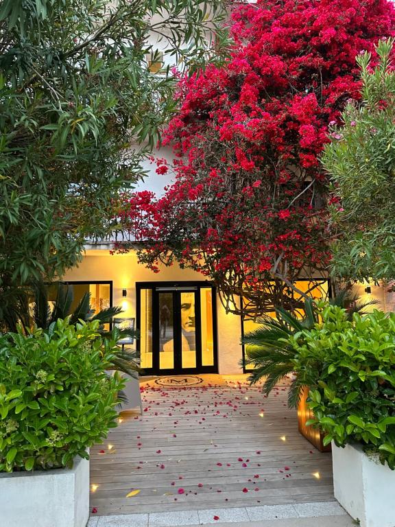 a walkway with red flowers in front of a building at Hôtel Le Mistral in Porto-Vecchio