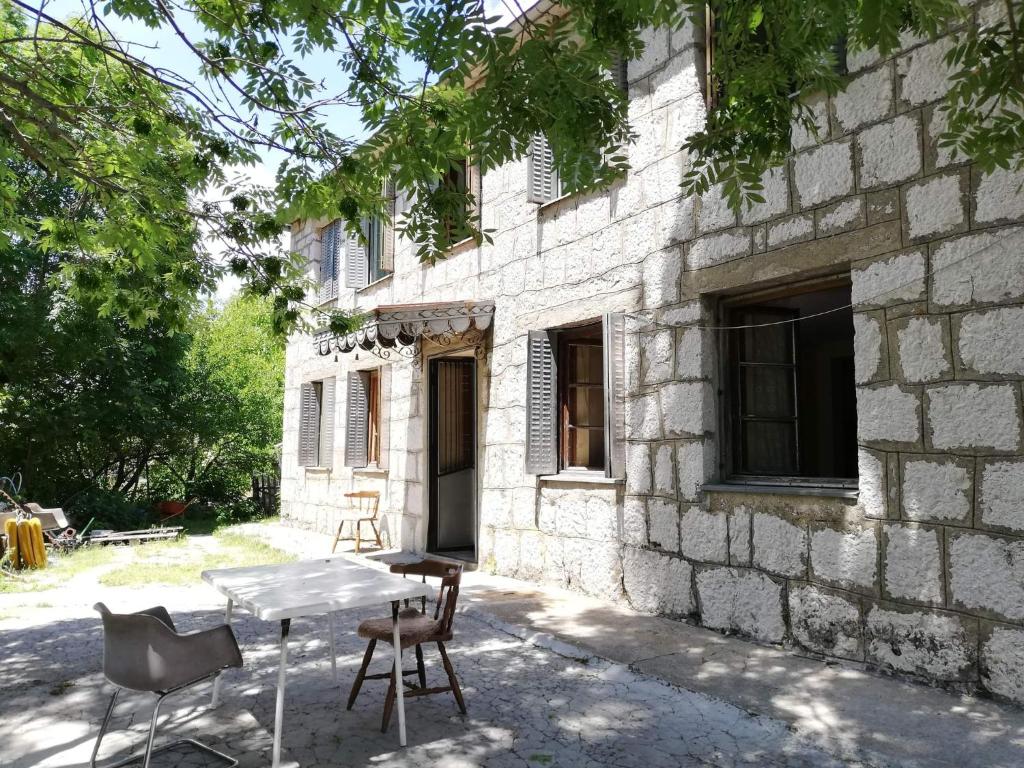 a table and chairs in front of a stone building at Leppo Guest House in Gacko