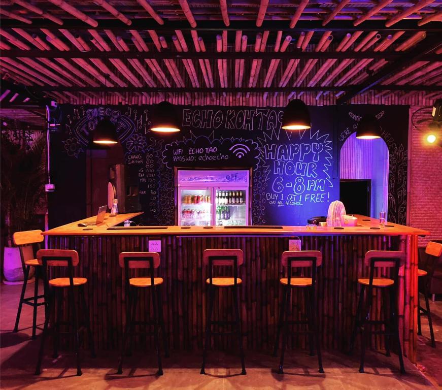 um bar com bancos numa sala com uma parede com escrita em Echo Hostel Koh Tao em Ko Tao
