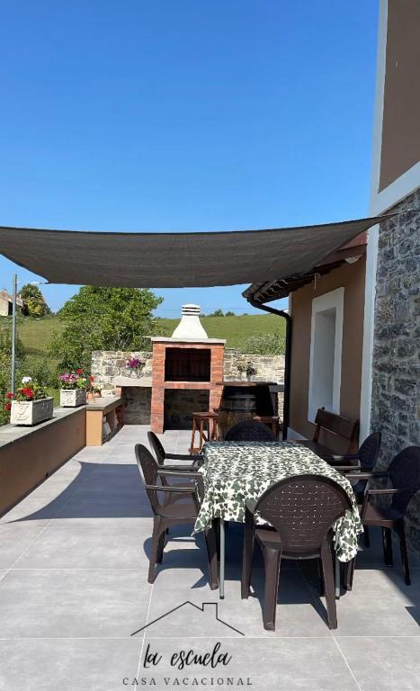 a patio with a table and chairs and a fireplace at Casa vacacional Escuela la Llera in Colunga