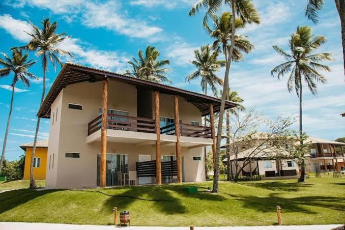 ein Haus mit Palmen davor in der Unterkunft Resort Asenza Bangalô Barão 503 in Pitimbu