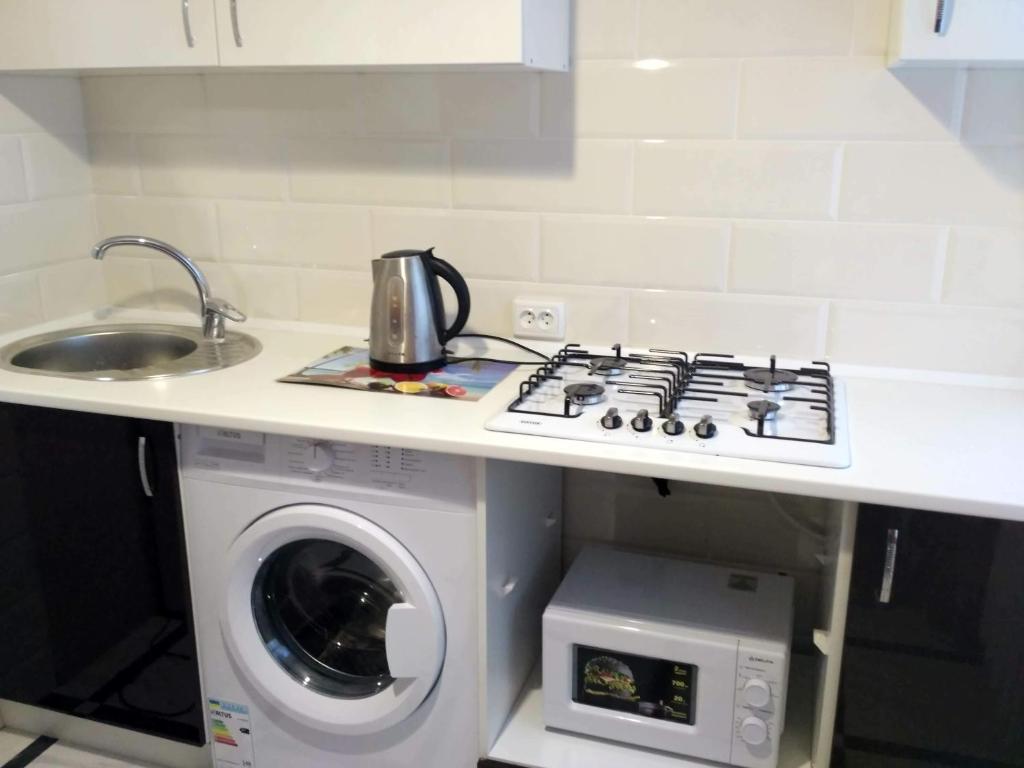 cocina con fogones horno superior junto a una lavadora en Подобово квартира в центрі міста, en Konotop