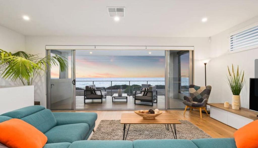 a living room with a blue couch and a table at Ocean At Seaford- Beachfront Luxury-Free Wifi in Seaford