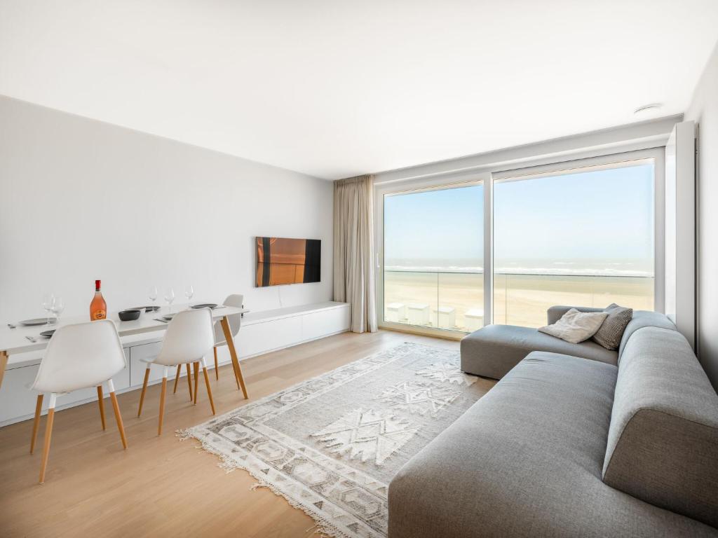a living room with a couch and a table with chairs at Zilverzand 202 new construction located on the beach in Koksijde