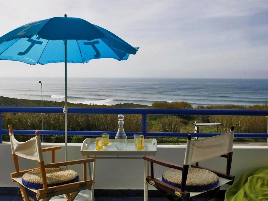 a table and chairs on a balcony with an umbrella at Páteo na Ericeira in Ericeira