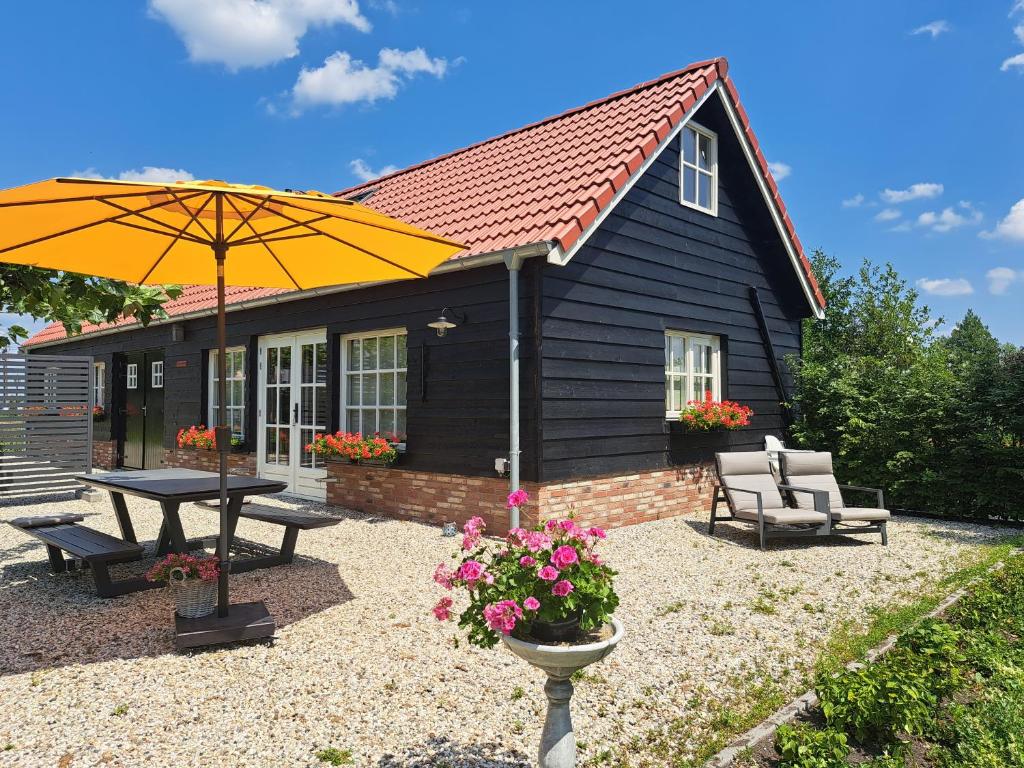 una piccola casa con tavolo da picnic e ombrellone di B&B De Oase a Bergambacht