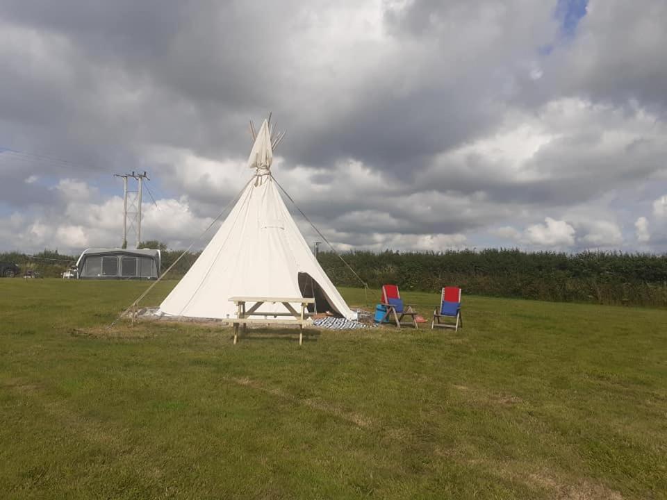 a teepee with two chairs and a table in a field at Hawk's View Tipi at Higher Hawksland Farm in Saint Issey