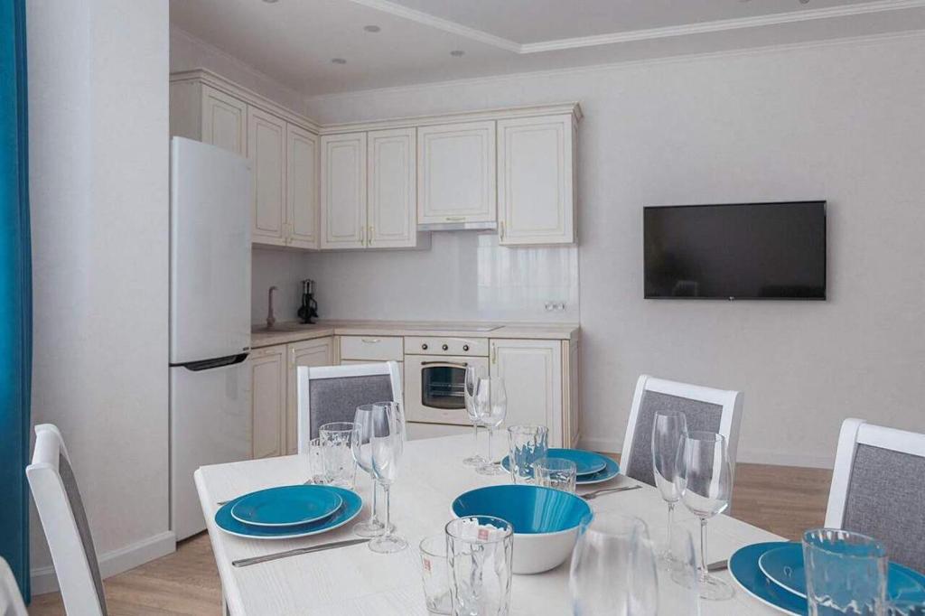 une cuisine avec une table blanche avec des assiettes bleues et des verres à vin dans l'établissement Arcadia 2nd Pearl Apartment, à Odessa