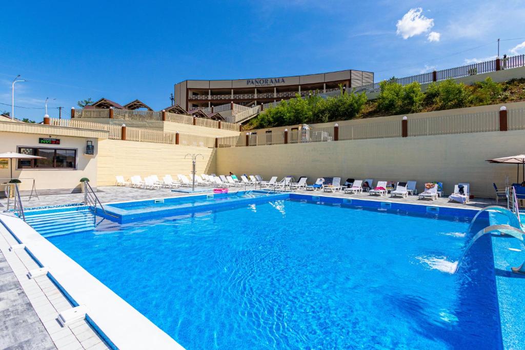 ein großer Pool mit Stühlen und ein Gebäude in der Unterkunft PANORAMA in Solotwyno