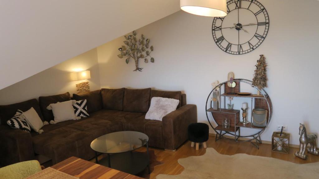 a living room with a couch and a clock on the wall at Apartmán AURIS in Veľká Lomnica