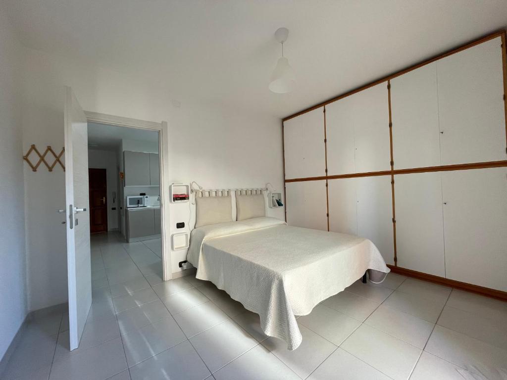 una camera bianca con un grande letto e una cucina di La Casa di Mia a Cagliari