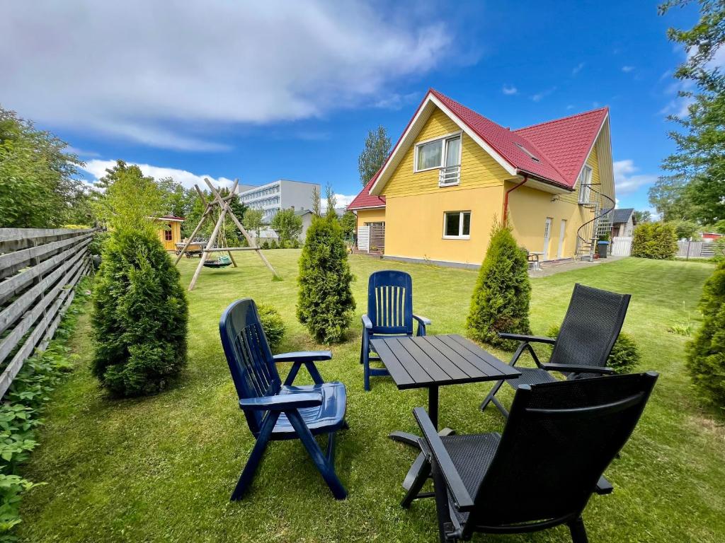 a yard with chairs and a table and a house at Metsa Apartments in Pärnu