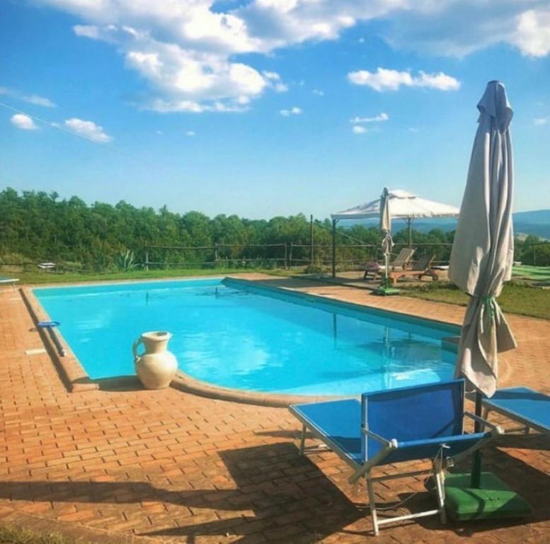 a swimming pool with a chair and an umbrella at Podere Umbro in Città della Pieve