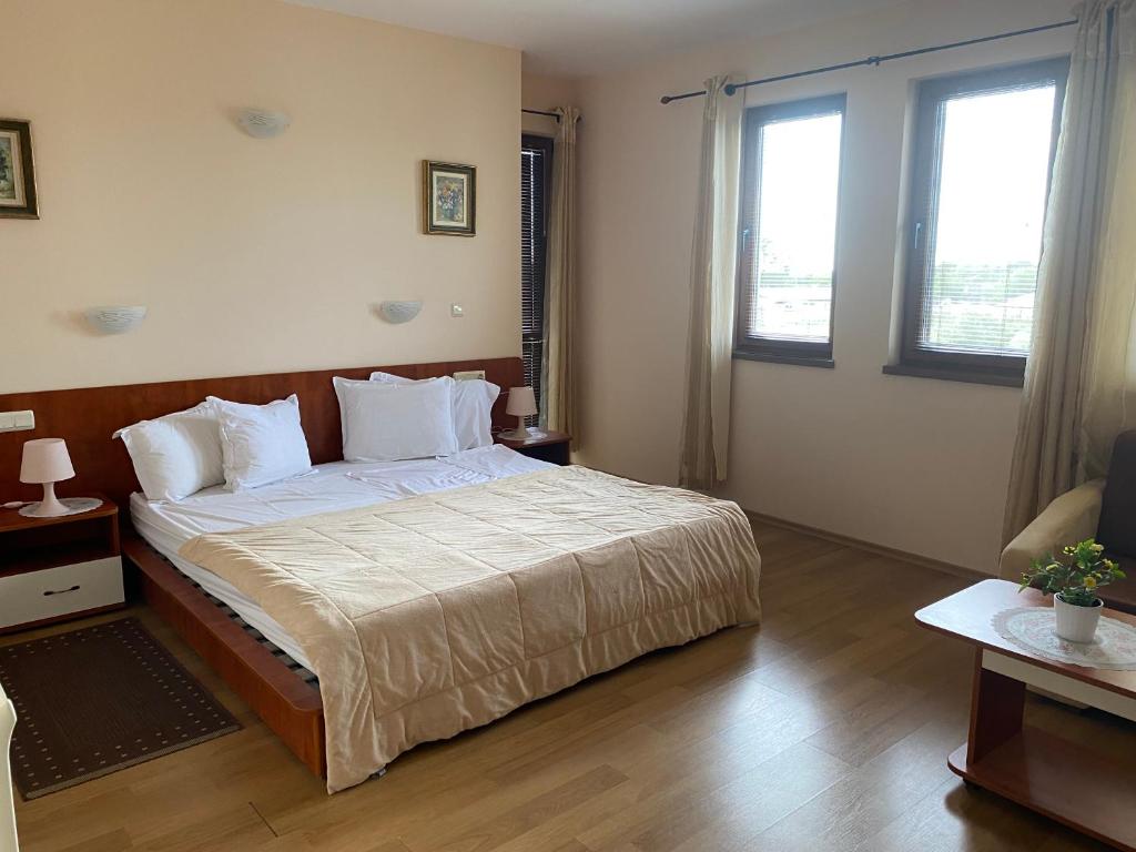 a bedroom with a large bed and two windows at Guest House Golden Flake 4km from Bolata beach in Bŭlgarevo