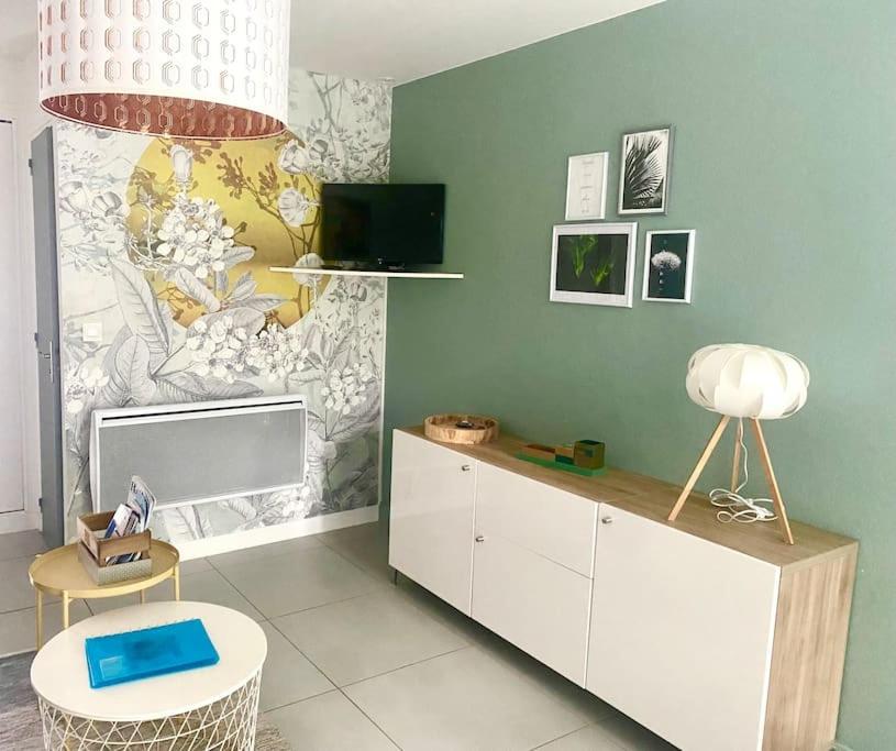 Elle comprend un salon avec une télévision et un bureau avec une lampe. dans l'établissement APPARTEMENT-JARDINET 300 m plage ST PALAIS SUR MER, à Saint-Palais-sur-Mer