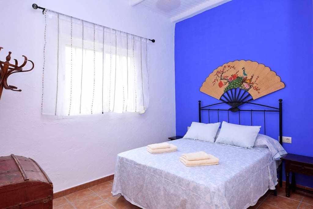 een blauwe slaapkamer met een bed met twee handdoeken erop bij Cortijo Algarrobo Casa de Campo tranquila in Carboneras