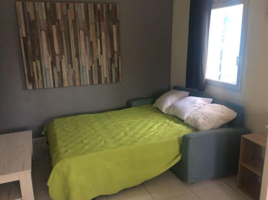 Un dormitorio con una cama verde y una ventana en Jolie petite villa climatisée proche de la mer, en Torreilles