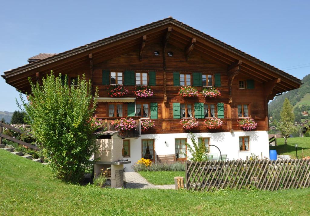 una gran casa de madera con flores. en Alpenchalet Spiher Gstaad Ferienwohnung im Parterre en Gstaad