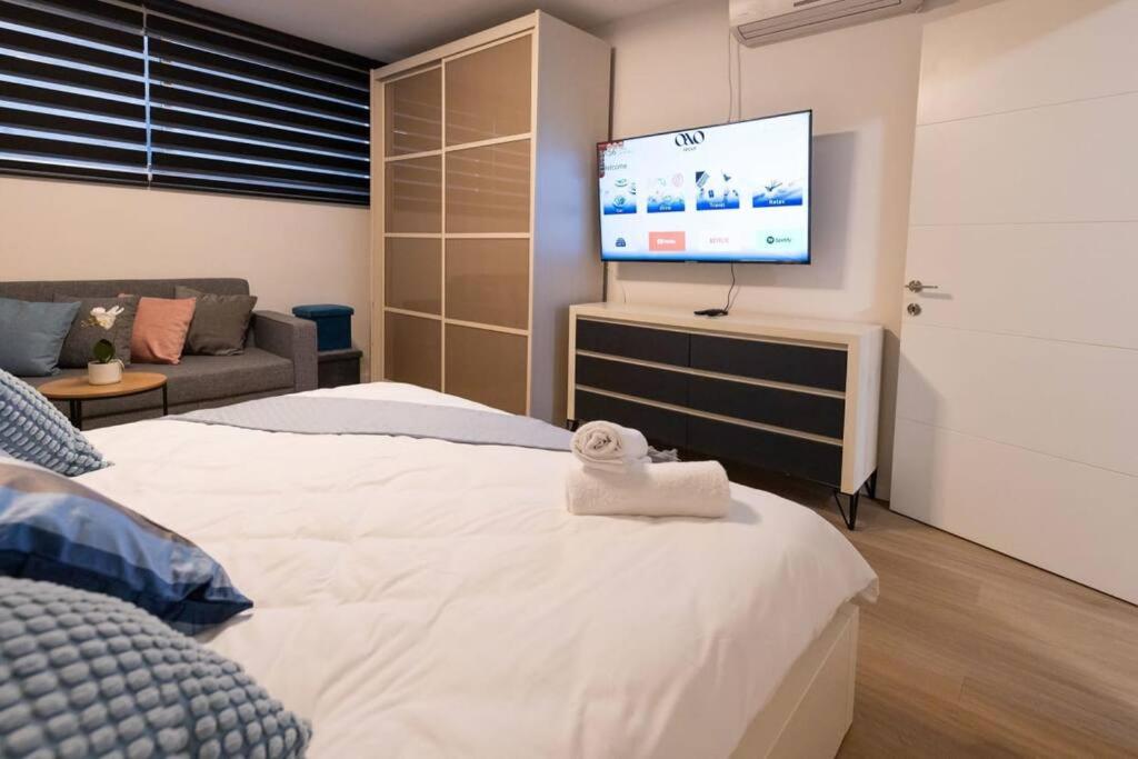1 dormitorio con 1 cama y TV de pantalla plana en O&O Group - The SeaGate Estate suites - Suite 1 en Rishon LeẔiyyon