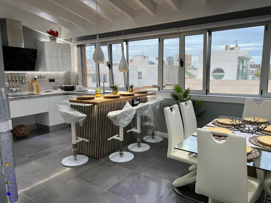 cocina con sillas blancas, mesa y barra en Apartamento Victorio Las Canteras, en Las Palmas de Gran Canaria