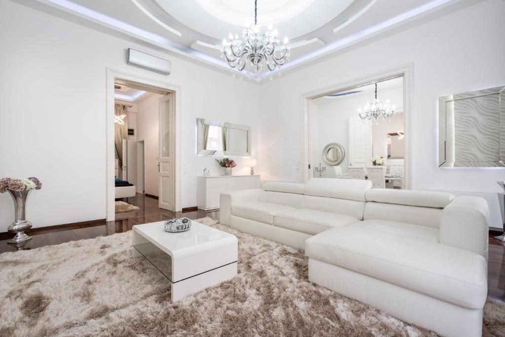 uma sala de estar com mobiliário branco e um lustre em Opera Balkony Luxury Apartment em Budapeste