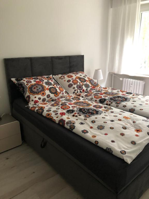 a bed with a comforter with flowers on it at Mieszkanie na Słupskiej in Ustka