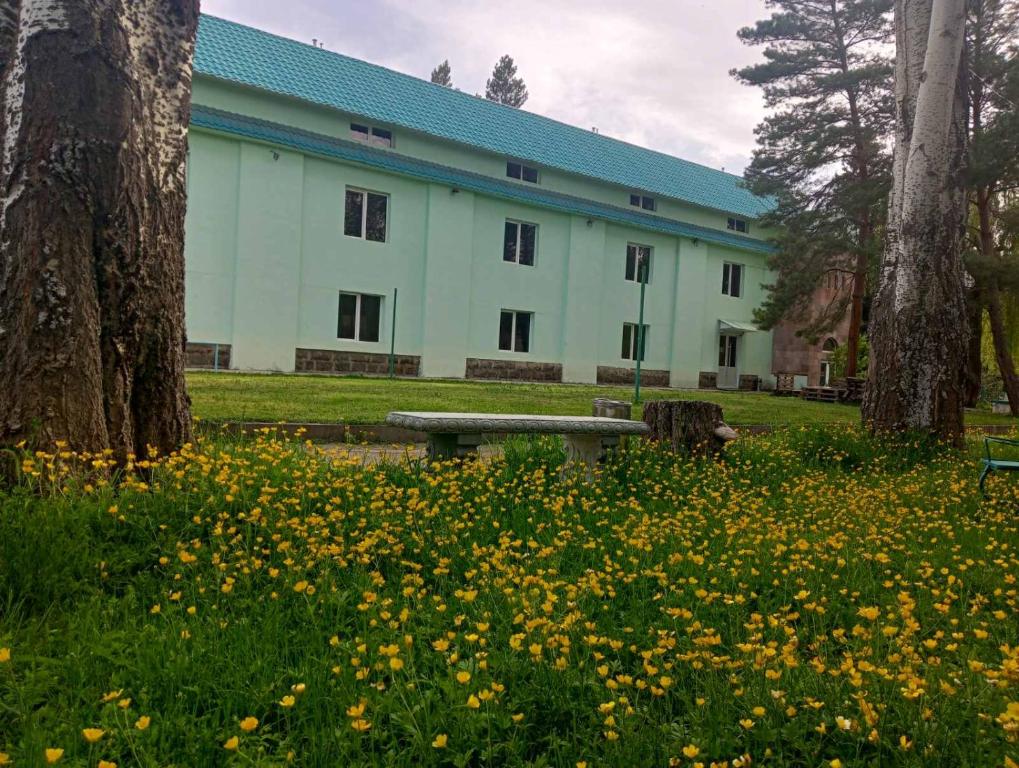 a building with a bench in a field of flowers at N&R Rest House in Tsaghkadzor